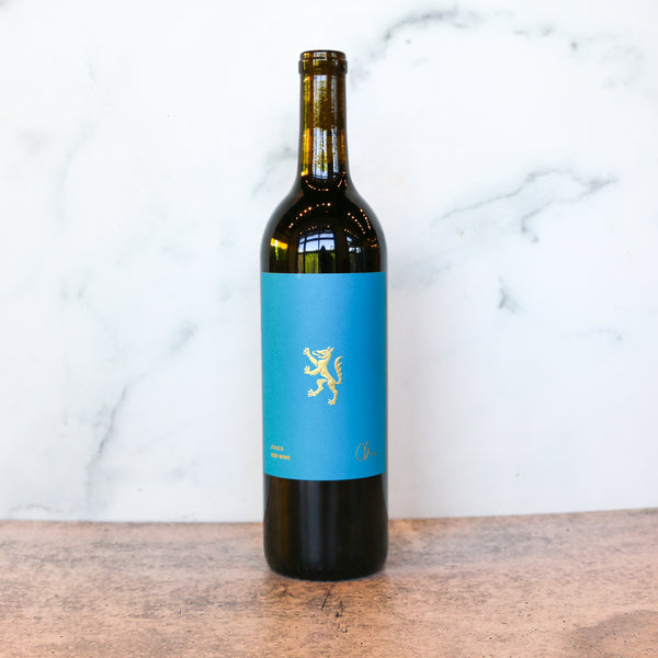 A bottle of CHRIS HAMILTON NAPA RED Blend available at TASTE across costal Virginia and Richmond and online at TASTE.online - Wine bottle with a blue label on a wooden surface and marble background