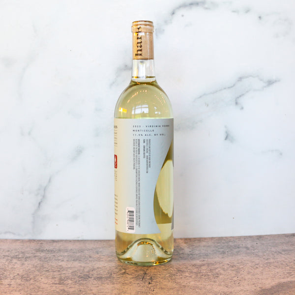 Bottle of white wine with a label on a marble background. This is Hark Vinyards Virginia Verde available at TASTE across costal Virginia and Richmond and online at TASTE.online