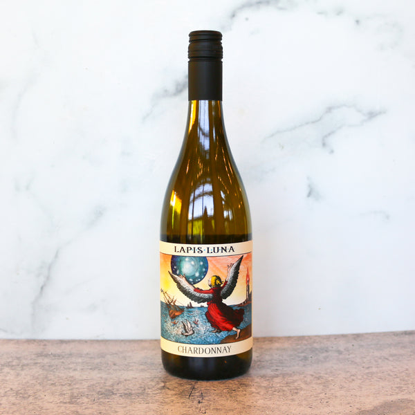 Wine bottle labeled 'Lapis Luna Chardonnay' on a wooden surface with a marble background available at TASTE across costal Virginia and Richmond and online at TASTE.online