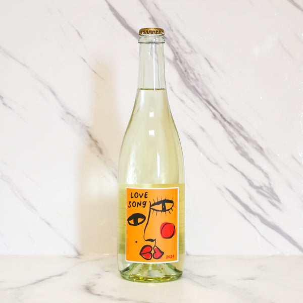 Bottle of 'Love Song' with an orange label featuring a face design on a marble background, available at TASTE across costal Virginia and Richmond and online at TASTE.online
