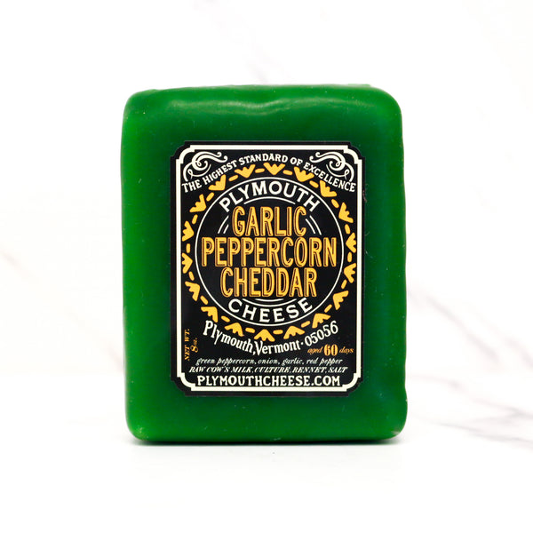 Green block of Plymouth Garlic Peppercorn Cheddar Cheese with a label on a white background