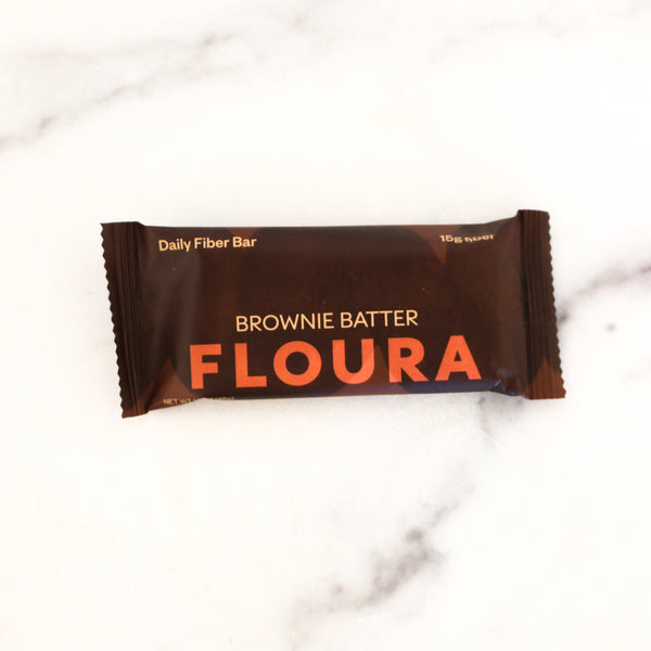 Floura Brownie Batter fiber bar on a marble surface
