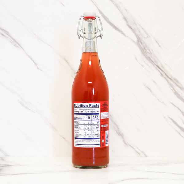 Bottle of red liquid with a nutrition facts label on a white background