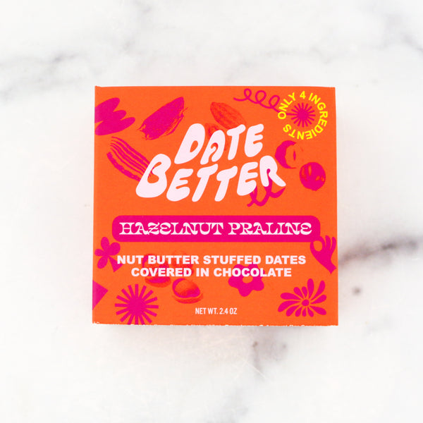 Orange packaging of 'Date Better' hazelnut pralines on a marble surface