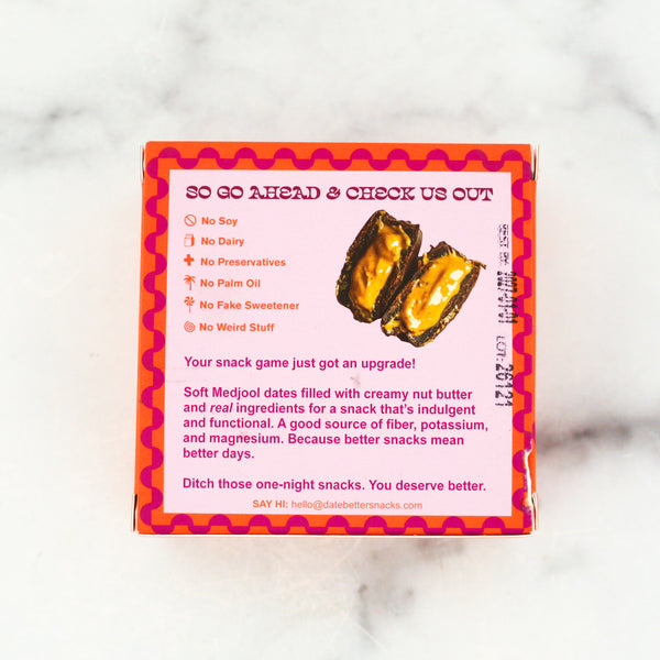 Back of a snack package with text and images of dates and nut butter on a white marble background