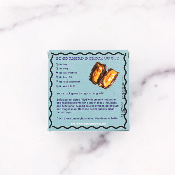 Box of Medjool dates filled with creamy nut butter on a marble surface