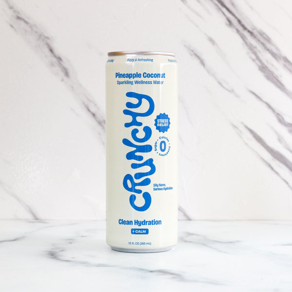 Can of Crunchy Pineapple Coconut sparkling wellness water on a marble background