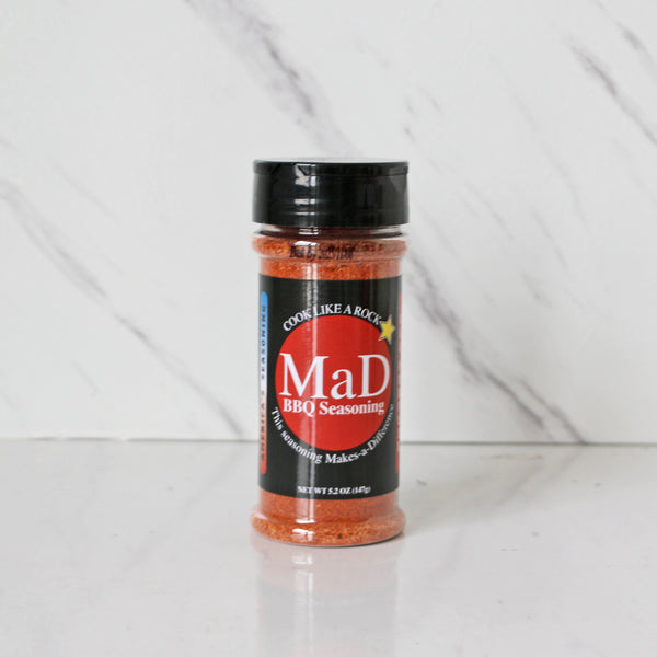 A 6.5oz shaker bottle of MAD BBQ Seasoning with a label that includes the brand name and the words 'Like a Rock'.