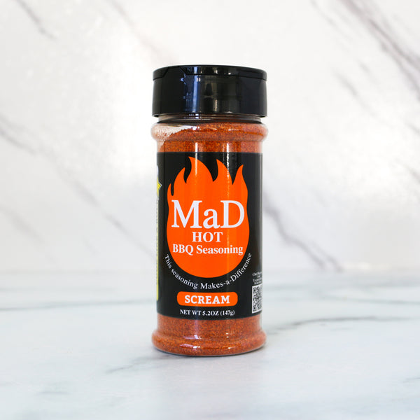 Spice jar, Mad Orange aka “scream” (hot BBQ) Seasoning  on a white marble background. Spice jar with label on a white background. All MaD Seasonings come from Matt Starcher, aka The MattDad, aka @themattdad, a culinary pro, instructor and contestant on Next Level Chef with Gordon Ramsay (Season 5). That chef-driven pedigree shows in every blend.  