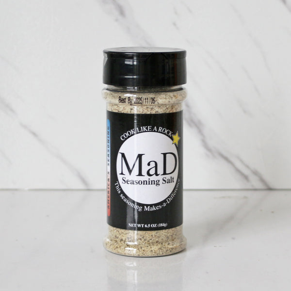 A shaker bottle of MAD Seasoning Salt on a marble surface.
