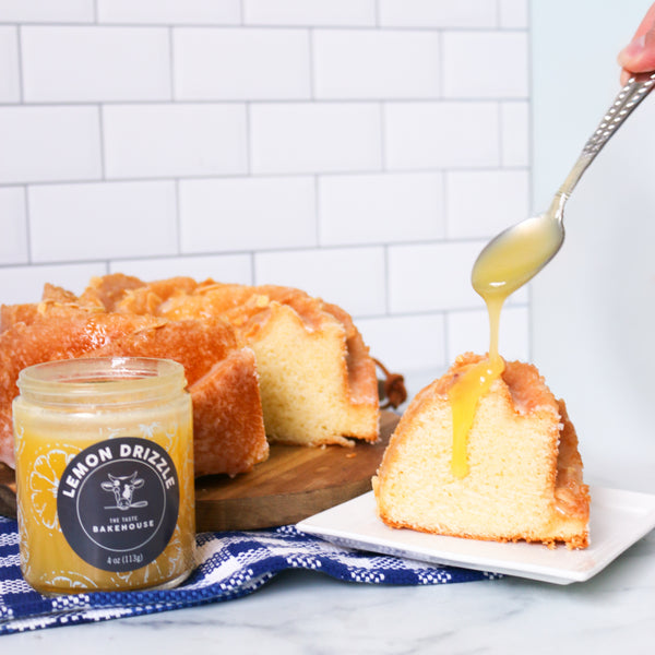 Taste bakehouse amaretto bundt cake with a jar of lemon drizzle and a slice on a plate.