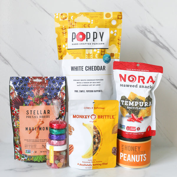 Assorted snack packages including Poppy, Nora, Stellar, and Monkey Brittle on a white background.
