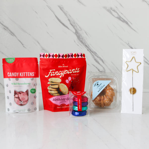 Collection of Birthday treats products including 'Candy Kittens' and 'Fancypants Birtday Cake Cookes' on a marble surface.