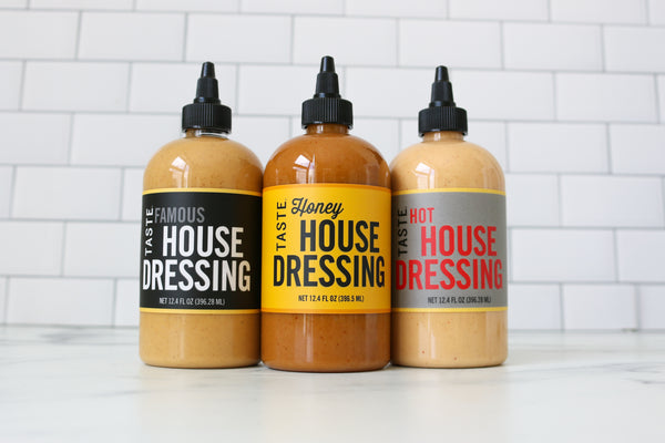 Three bottles of TASTE house dressing with different flavors on a white background