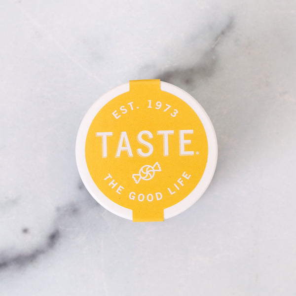 Round yellow label with 'Taste. The Good Life' text on a marble background