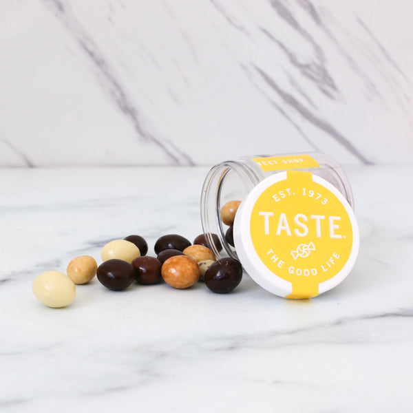 Jar of assorted coffee chocolates with a 'Taste the Good Life' lid on a marble surface