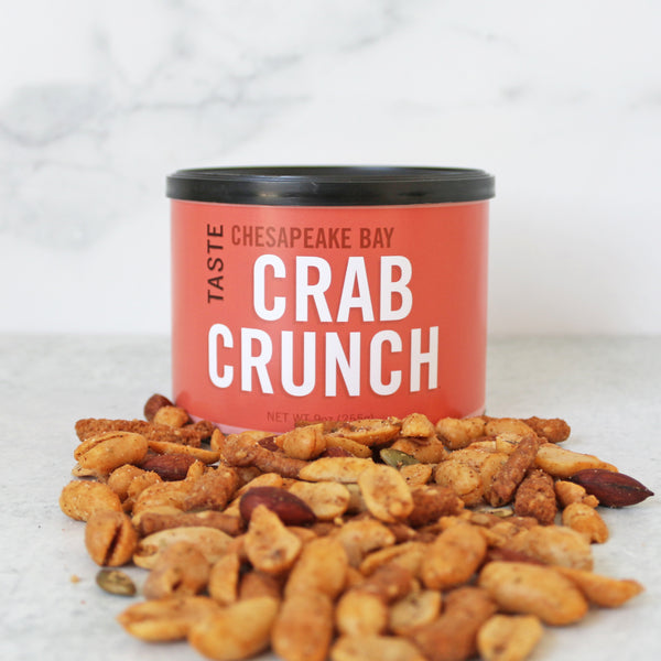 A can of TASTE Crab Crunch snack mix with a variety of nuts and snacks spilling out in front of it.