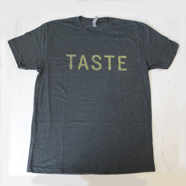 Charcoal gray heather t-shirt with 'TASTE' printed in letters consisting of tiny graphics of food related items, yellow on a white background