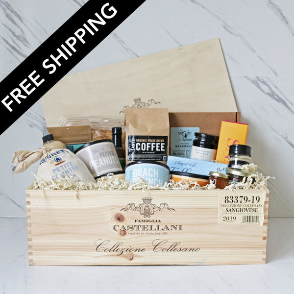 Wooden gift box with various items including coffee and snacks, branded 'Famiglia Castellani', on a light background.
