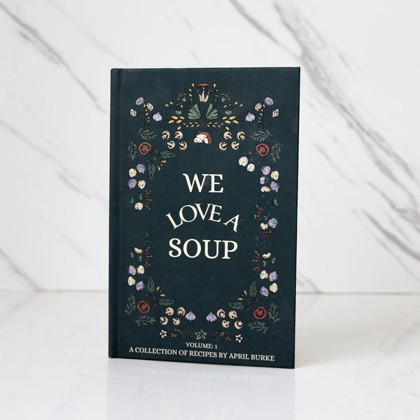 April Burke's book titled 'We Love A Soup' with floral design on a white background