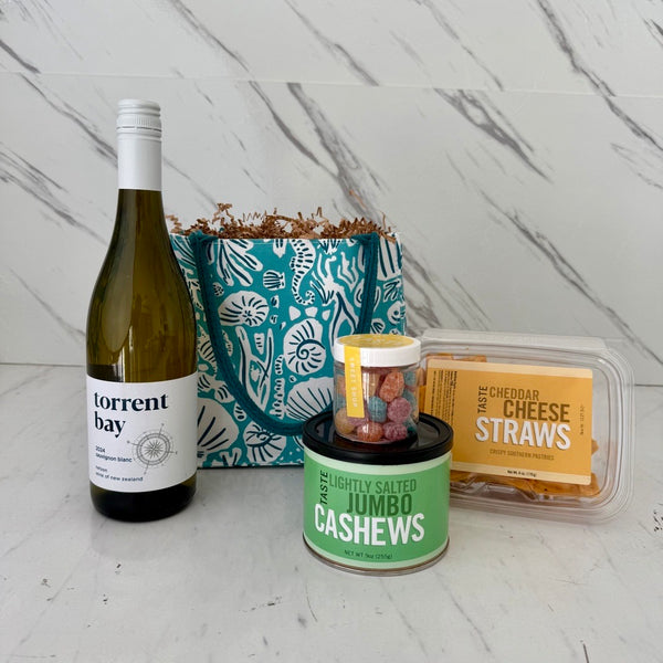 Wine bottle, cashew container, and cheese straws on a marble surface