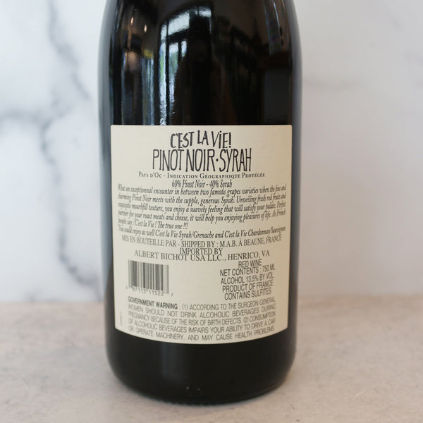 back of A bottle of C'est La Vie Pinot Noir - Syrah red wine with a label, placed on a marble surface.