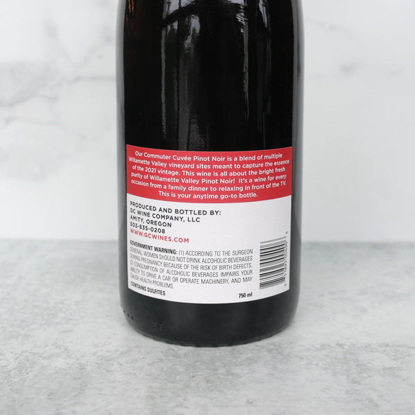 back of the bottle of commuter cuvee on a white marble background