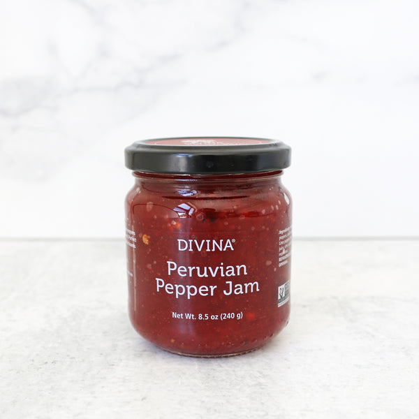 A jar of Divina Peruvian Pepper Jam on a light background, showing a red pepper spread with visible pieces of pepper.