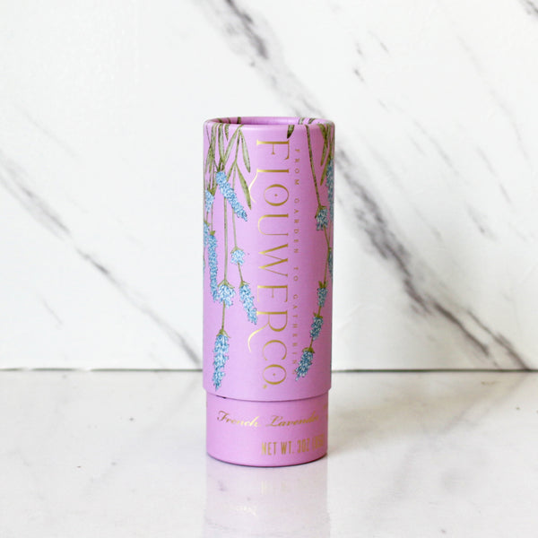 A cylindrical container of Flouwer Co. French Lavender Finishing Sugar with a pink label featuring illustrations of lavender flowers.