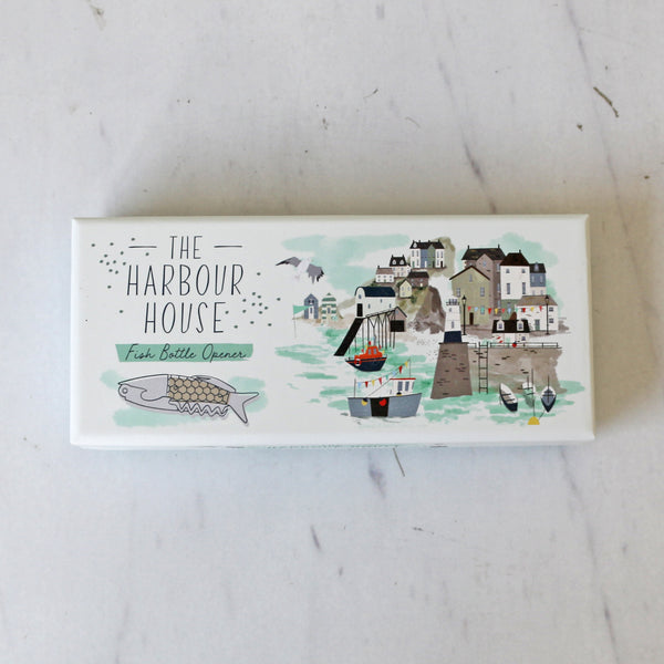 Box with 'The Harbour House' branding and a coastal illustration on a light background that holds a Fish Bottle opener with a fishscale wood handle