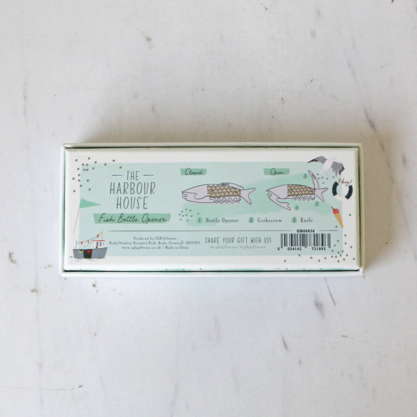 Box with 'The Harbour House' branding and a coastal illustration on a light background that holds a Fish Bottle opener with a fish scale wood handle