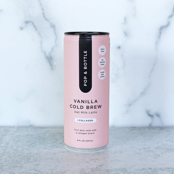 A pink can of Pop & Bottle Oat Milk Latte in Vanilla Cold Brew flavor, with the text 'OAT MILK LATTE', 'VANILLA', 'cold brew', and '100% plant-based' displayed on the can.