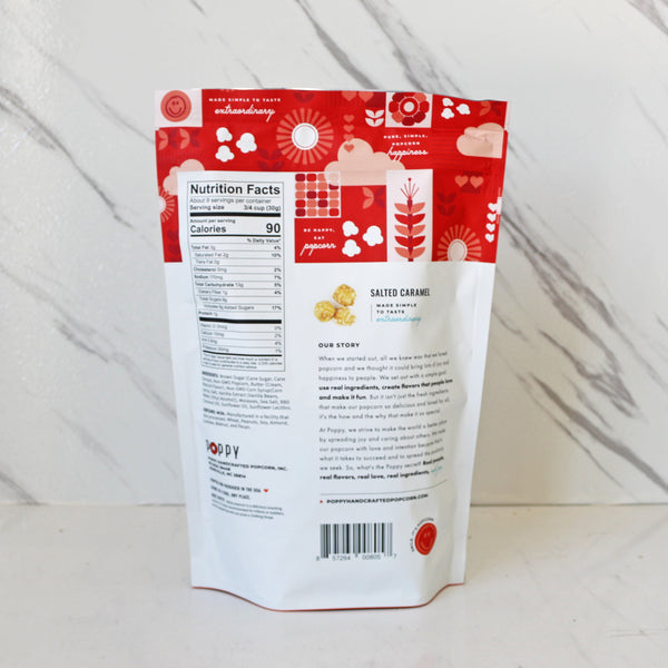 a bag of poppy hand-crafted popcorn salted caramel in front of a marble background. 