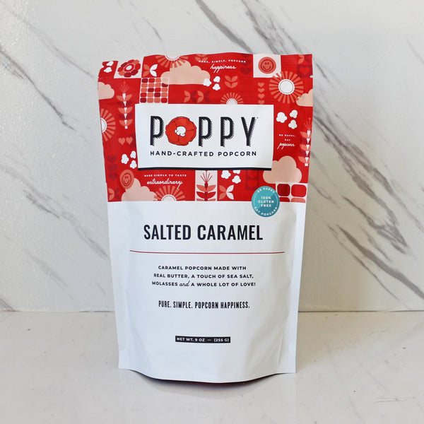 a bag of poppy hand-crafted popcorn salted caramel in front of a marble background. 