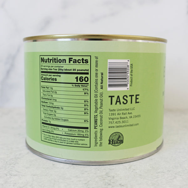 A green cylindrical tin labeled 'SALT FREE VIRGINIA PEANUTS' with a pile of raw peanuts in front of it on a marble surface.