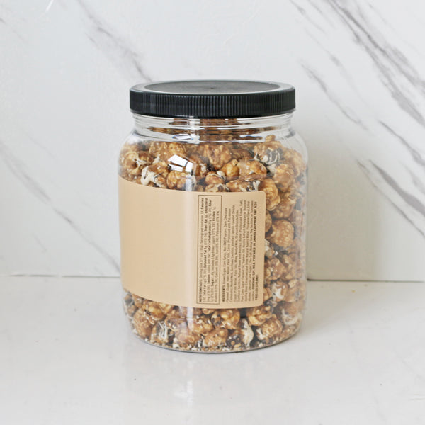 A clear jar filled with caramel popcorn drizzled with white and dark chocolate, labeled 'TASTE Chocolate Drizzle Popcorn'.