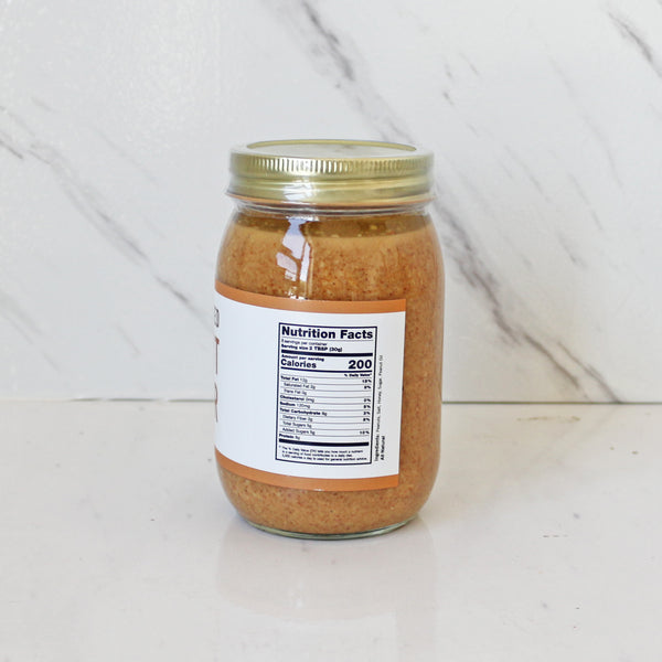 Ajar of TASTE Honey Roasted Peanut Butter on a white table with marble background 
