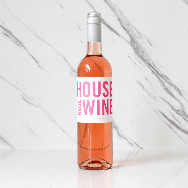 Bottle of TASTE House rose wine with a pink label on a marble background