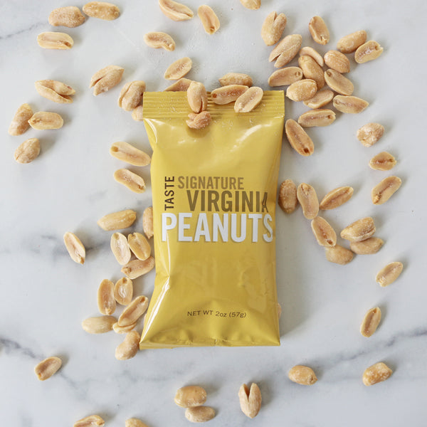 A yellow 2oz snack pack of TASTE Virginia Peanuts spilled with peanuts scattered around it.