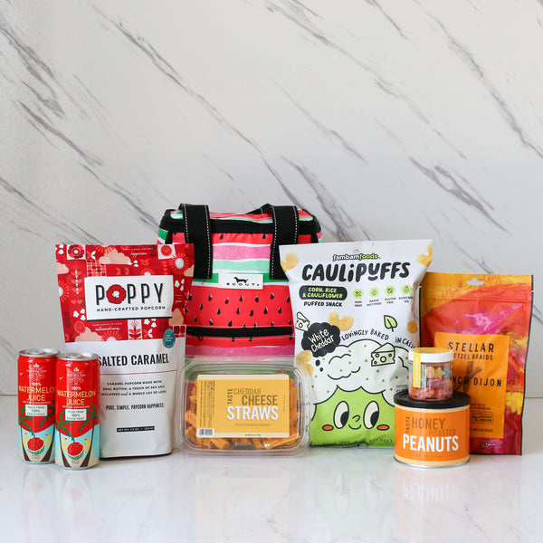 Assorted snack products including bags and containers on a white surface with a light gray marble background.