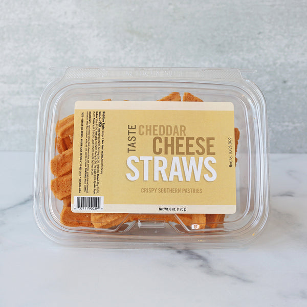 A resealable plastic container of TASTE Cheddar Cheese Straws on a marble surface.