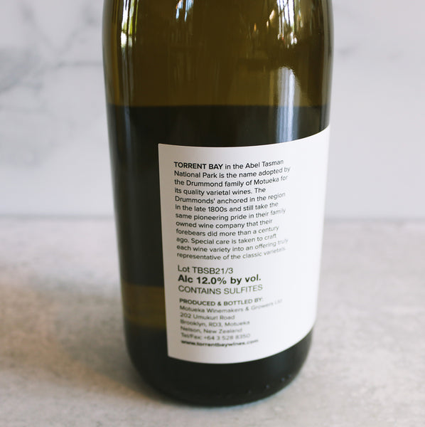 The back of a bottle of Torrent Bay Sauvignon Blanc wine positioned in front of a marble background.