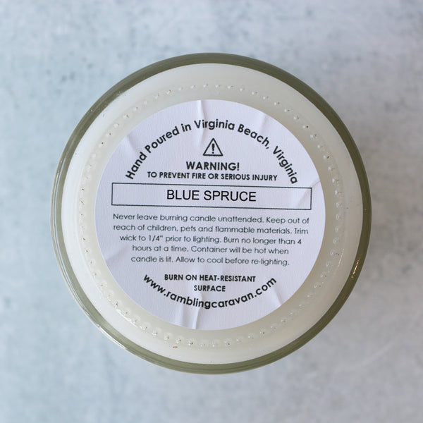 A jar candle with a white label that reads 'VIRGINIA LOVE' on a blue and green striped background, placed on a marble surface.