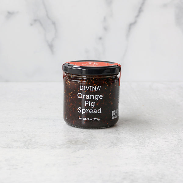 A jar of Divina Orange Fig Spread on a marble background.