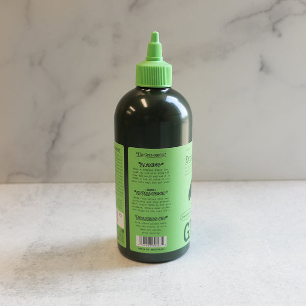 A bottle of Graza 'Drizzle' Extra Virgin Olive Oil with a green cap, labeled for culinary use.