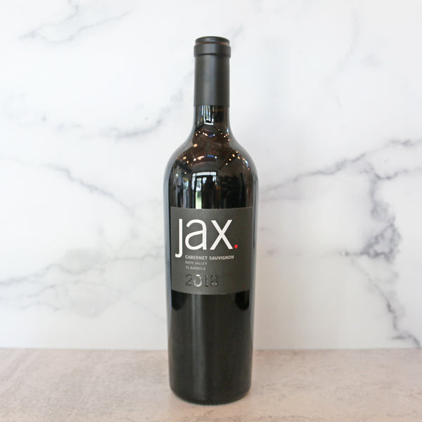 A bottle of JAX Cabernet Sauvignon 2018 wine positioned on a marble surface with a white background.