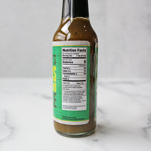 A bottle of Speedy's Citrus Jalapeno Hot Sauce on a marble surface.