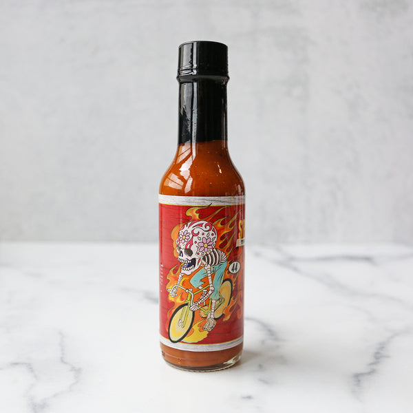 A bottle of Speedy's Original Hot Sauce on a marble surface.