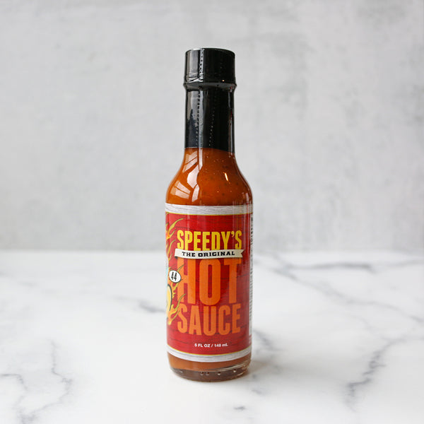 A bottle of Speedy's Original Hot Sauce on a marble surface.