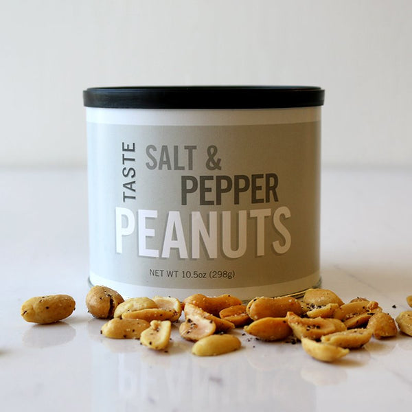 A canister labeled 'SALT & PEPPER PEANUTS' with a scattered pile of peanuts in front of it on a white surface.